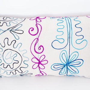 May include: White pillow with embroidered floral and paisley designs in blue, pink, and black thread.