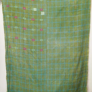 May include: A green textile with a blue grid pattern and pink and white accents. The fabric has a grid design created by blue lines, with pink and white details. The textile appears to be lightweight and possibly handmade, with a vintage aesthetic.