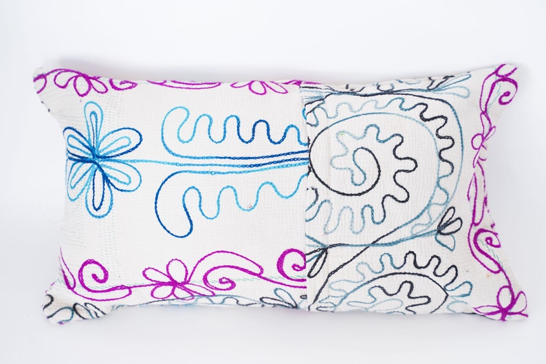 May include: White rectangular pillow with embroidered floral designs in blue, pink, and black.