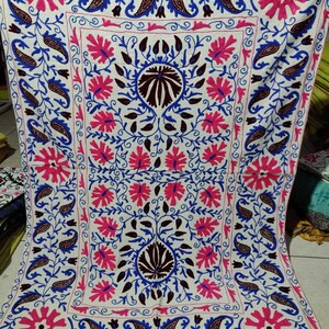 May include: White cotton fabric with intricate embroidery in pink, blue, and brown. The design features floral motifs and paisley patterns.