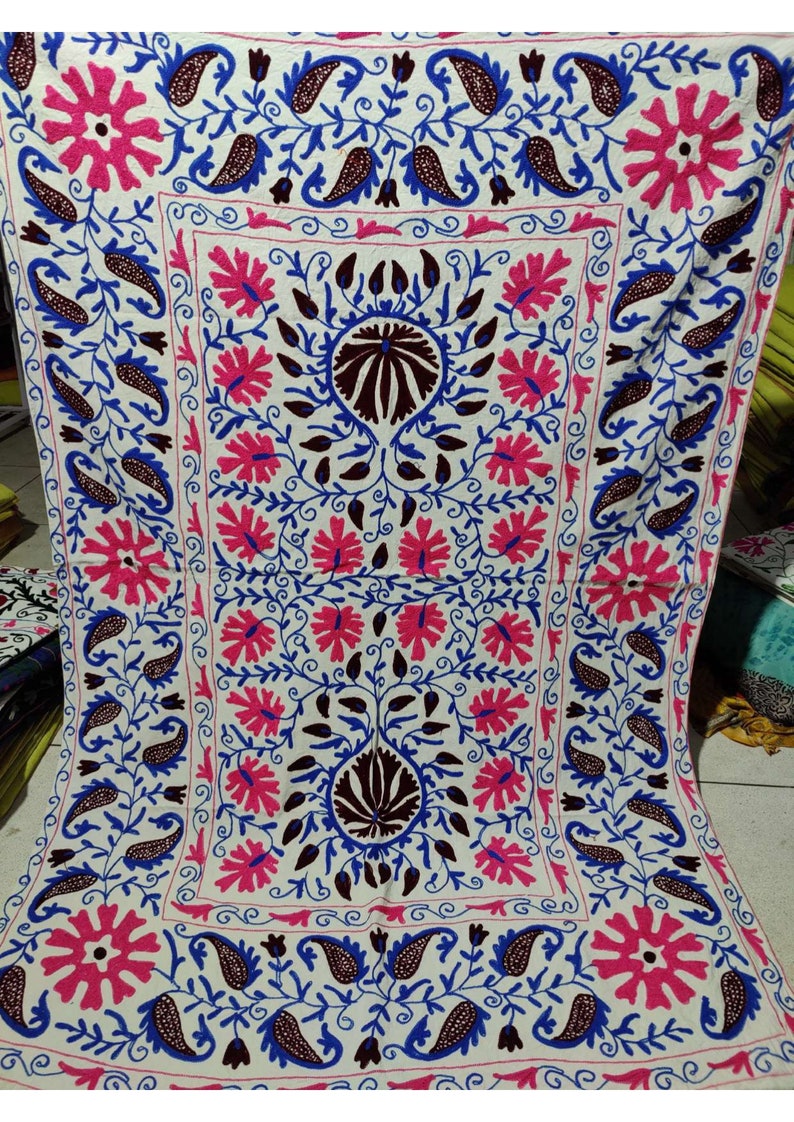 May include: White cotton fabric with intricate embroidery in pink, blue, and brown. The design features floral motifs and paisley patterns.