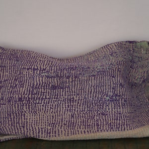 May include: A purple and white patterned throw pillow with a zipper closure.