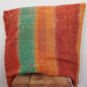 Puede incluir: Una almohada de tiro a rayas de colores con un diseño cosido a mano. La almohada está hecha de una tela suave y texturizada y presenta tonos de naranja, amarillo, verde y rojo.