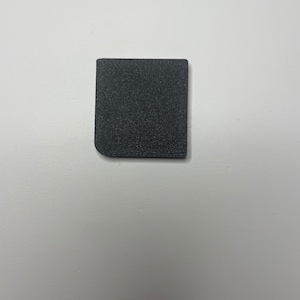 May include: A small, black, square-shaped piece of foam.