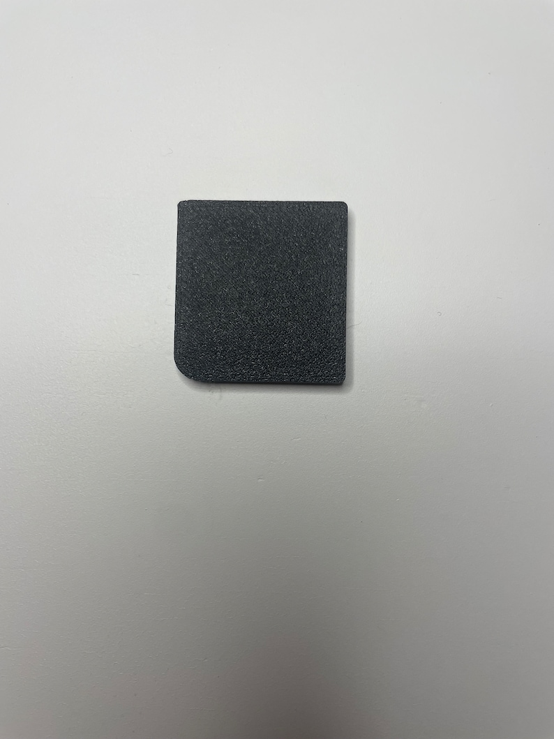 May include: A small, black, square-shaped piece of foam.