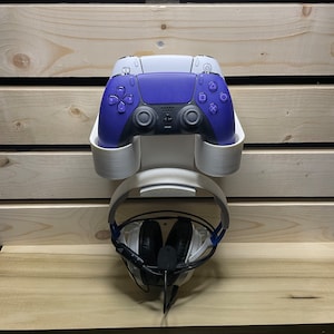 May include: White wall mount with a purple and white video game controller and a white headset with black earcups.