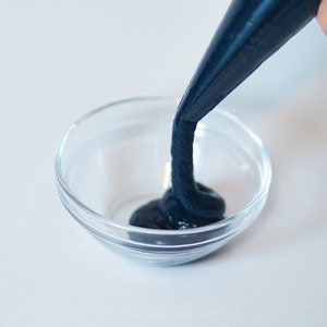 Könnte beinhalten: Ein dunkelblauer Frosting wird in eine durchsichtige Glasschüssel gefüllt.