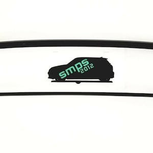 May include: Black car part with a curved frame and a straight bar below it. The text "SMPS 2012" is in the centre, with a car silhouette. The part is likely an automotive component.