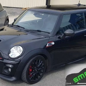 May include: A black Mini Cooper S with a black grille, red trim, and black alloy wheels. The car has a sunroof and tinted windows. The car is parked on a paved surface.