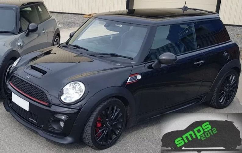 May include: A black Mini Cooper S with a black grille, red trim, and black alloy wheels. The car has a sunroof and tinted windows. The car is parked on a paved surface.