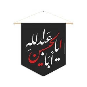 May include: Black pennant banner with Arabic calligraphy in white and red. The banner is suspended from a wooden dowel with a string for hanging. The text is a religious phrase.