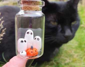 Cute miniature ghost family with pumpkin inside a mini haunted glass bottle