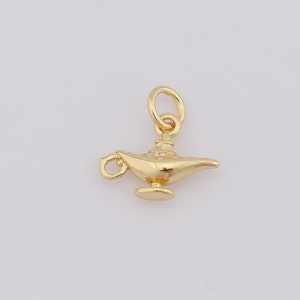 May include: A gold-colored genie lamp charm pendant. The lamp has a detailed design and a small loop at the top for attaching to a necklace or bracelet.