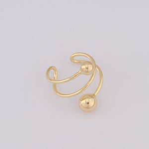 Puede incluir: Pendiente de aro de oro con dos bolas redondas. El pendiente está hecho de un alambre fino que se retuerce en forma de espiral.