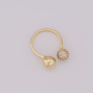 Puede incluir: Un anillo de oro con dos bolas redondas, una con piedras brillantes transparentes y la otra lisa.