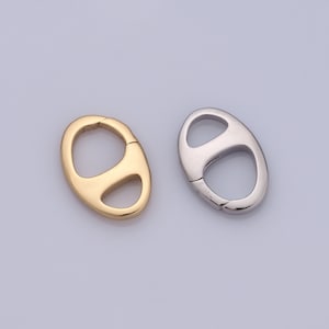 May include: Two oval-shaped metal clasps, one gold and one silver, with a spring-loaded opening. These clasps are used for attaching jewellery or other items.