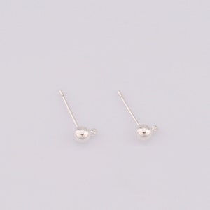 May include: A pair of silver ball stud earrings.