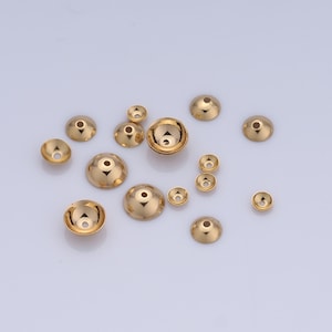 以下が含まれることがあります： さまざまなサイズの金色の金属製ビーズキャップのコレクション。キャップは丸型で、底が平らで、中央に小さな穴があります。
