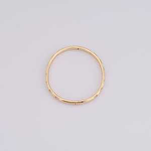 May include: A gold bangle bracelet with small, clear stones set into the band.