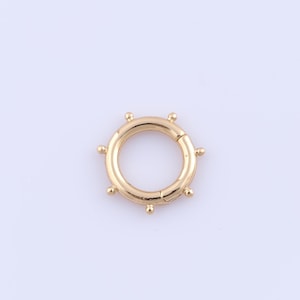 Può includere: Anello in metallo dorato con un design circolare e piccole sfere decorative attorno al bordo.