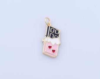 Può includere: Un ciondolo color oro a forma di barretta di cioccolato. La parte superiore è nera, il centro bianco e la parte inferiore rosa con due cuori rossi. Il ciondolo ha un anello dorato per attaccarlo a una collana o un braccialetto.