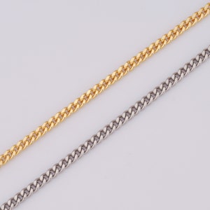May include: Two curb chains, one gold and one silver, laid out on a white surface.