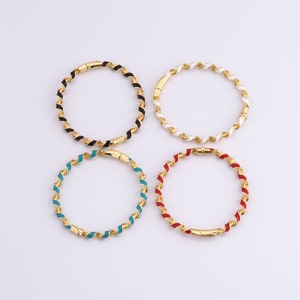 Puede incluir: Cuatro pulseras de oro con rayas de esmalte de diferentes colores. Las pulseras están retorcidas y tienen un cierre magnético.