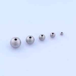 May include: Five silver-colored, textured beads of varying sizes are arranged diagonally on a light blue background. Each bead has a small, dark hole. The largest bead is approximately 0.75 inches in diameter, while the smallest is about 0.25 inches.