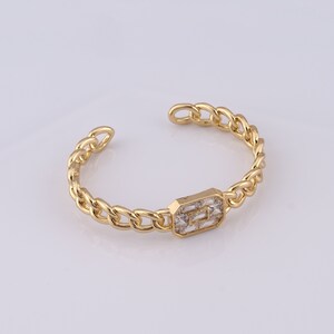 May include: A gold chain bracelet with a rectangular clear crystal accent.