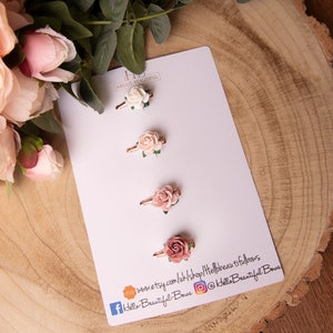 May include: Three pink and white flower hair clips on a white card with the text "Hello Beautiful Bows" and social media handles.