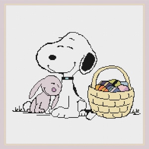 May include: Cross-stitch design showing Snoopy, a white dog with black ears, and a small purple bunny. They sit beside a woven basket filled with colourful Easter eggs. The design is on a white background.