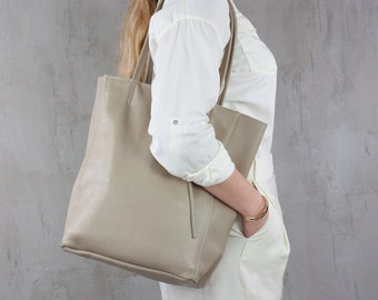Könnte beinhalten: Eine große, hellbeige Ledertasche mit einem einzigen Henkel oben und zwei Schultergurten. Die Tasche ist aus weichem, strukturiertem Leder gefertigt und hat ein geräumiges Innenleben.