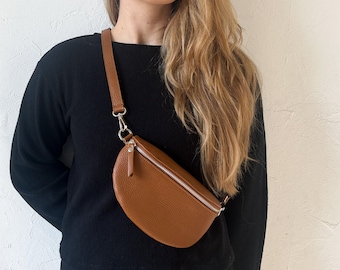 Petit sac banane en cuir cognac pour femme, avec large bandoulière interchangeable.