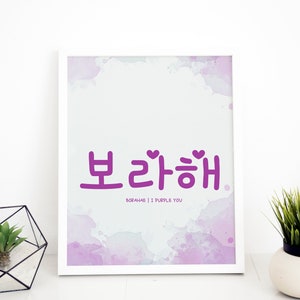 May include: White framed art print with the Korean phrase "Borahae" in purple, meaning "I Purple You." The background features a watercolor wash in shades of purple and white. The print is displayed on a white surface.