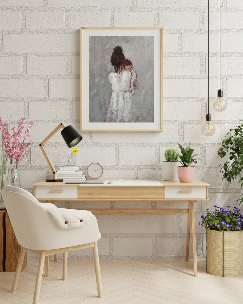 May include: A painting of a woman in a white dress holding a baby. The painting is framed in a light wood frame and is hanging on a white brick wall.