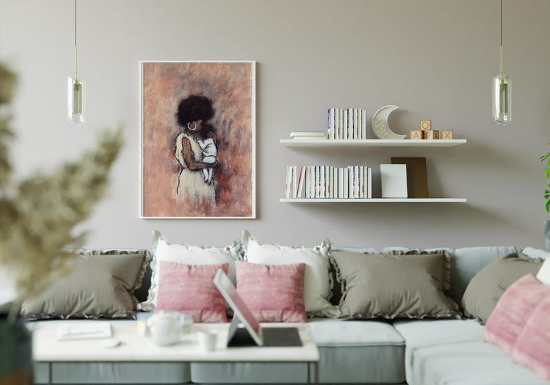 May include: A framed art print depicting a woman cradling a baby, in peach, brown, and white hues. The artwork hangs above a grey sofa with pink and grey cushions. The room is decorated with shelves, books, and a decorative crescent moon.