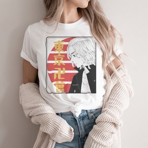 May include: White t-shirt with a graphic print of a cartoon character with blonde hair. The graphic also includes Japanese text and a red and white sun design.
