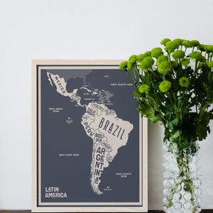 May include: A framed map of Latin America with a light blue background and beige country outlines. The map shows the countries of Mexico, Venezuela, Colombia, Ecuador, Peru, Bolivia, Paraguay, Chile, Argentina, Uruguay, Brazil, Guyana, Suriname, and French Guiana. The map is titled "Latin America" in beige text.