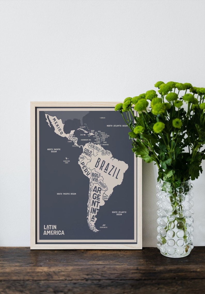 May include: A framed map of Latin America with a light blue background and beige country outlines. The map shows the countries of Mexico, Venezuela, Colombia, Ecuador, Peru, Bolivia, Paraguay, Chile, Argentina, Uruguay, Brazil, Guyana, Suriname, and French Guiana. The map is titled "Latin America" in beige text.