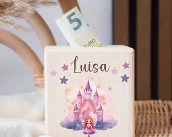May include: A wooden money box featuring a princess castle design. The box is light-coloured with the name "Luisa" and star accents. A five Euro note is visible in the slot. A crocheted horse toy is in the background.