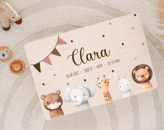 May include: A wooden plaque with a pink and brown bunting design. The plaque has the name "Clara" written in brown cursive lettering. The text "18.08.2023 - 3100 G - 49CM - 05:45 UHR" is written in black. The plaque is decorated with illustrations of a bear, elephant, giraffe, rabbit, and lion.
