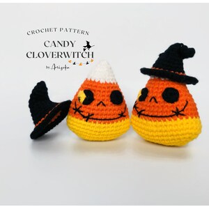 May include: Crochet pattern for Candy Cloverwitch. The image shows two crocheted candy corn figures with smiling faces and black witch hats. The candy corn is orange, yellow, and white. The text "CROCHET PATTERN CANDY CLOVERWITCH by Arizuka" is at the top.