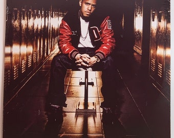 May include: Album cover featuring J. Cole, seated on a bench in a locker room setting. He wears a red and black varsity jacket with the letter "D" and a watch. The album title "Cole World: The Sideline Story" is displayed at the bottom.