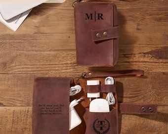 May include: A brown leather tech organiser with the initials "MR" embossed on the front. The open organiser reveals compartments for chargers and accessories. The text "We'll miss you, but we know you'll come back with amazing stories" is printed on the inside.