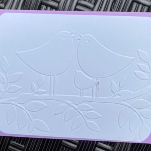 Tarjeta con una familia de pájaros felices en relieve para un amigo. Tarjeta en blanco con sobre colorido. Sobre morado. Pájaros en una tarjeta. Diseño en relieve. Tarjetas de notas.