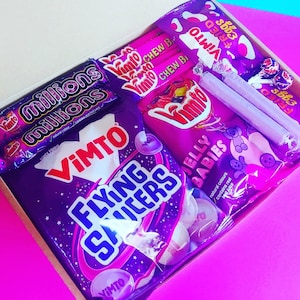 May include: A purple gift box filled with various purple and pink sweets. The box contains bags of Vimto Flying Saucers, Vimto Chews, Millions sweets, Jelly Babies, and Vimto Fried Eggs.