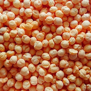May include: A close-up image of a large pile of small, round, orange-coloured sweets. The sweets are smooth and shiny, and they look like they would be delicious.