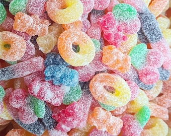 May include: A close-up of a variety of colorful, sugary candies. The candies are shaped like rings, bears, and other fun shapes. They are covered in a white, sugary coating.