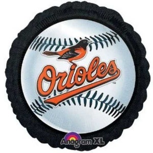 May include: A baseball-shaped balloon featuring the Baltimore Orioles logo. The design includes a baseball with black stitching, the team name in orange script, and a bird graphic. The balloon is surrounded by a black, scalloped border.