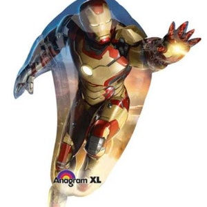 May include: A red, gold, and silver Iron Man character foil balloon. The balloon is shaped like Iron Man flying with his arms outstretched. The balloon has the text "Anagram XL" printed on it.